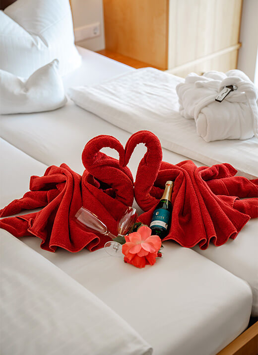 Romantische Handtuchdekoration in Herzform auf einem Bett
