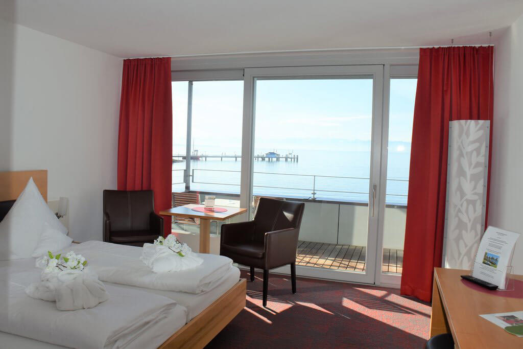 Schlafzimmer mit Seeblick, Balkon und roten Vorhängen