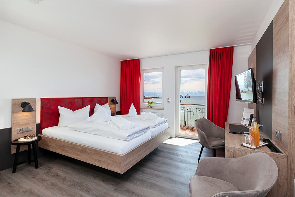 Geräumiges Schlafzimmer mit Doppelbett, roten Vorhängen und Sitzecke