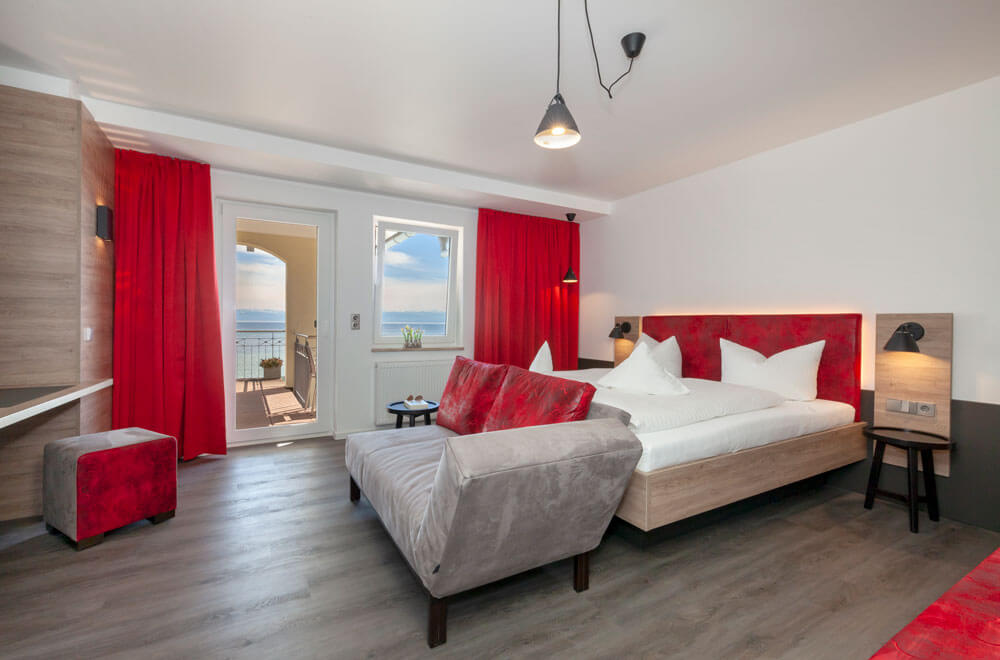 Helles Schlafzimmer mit Sofa, Doppelbett und Balkonblick