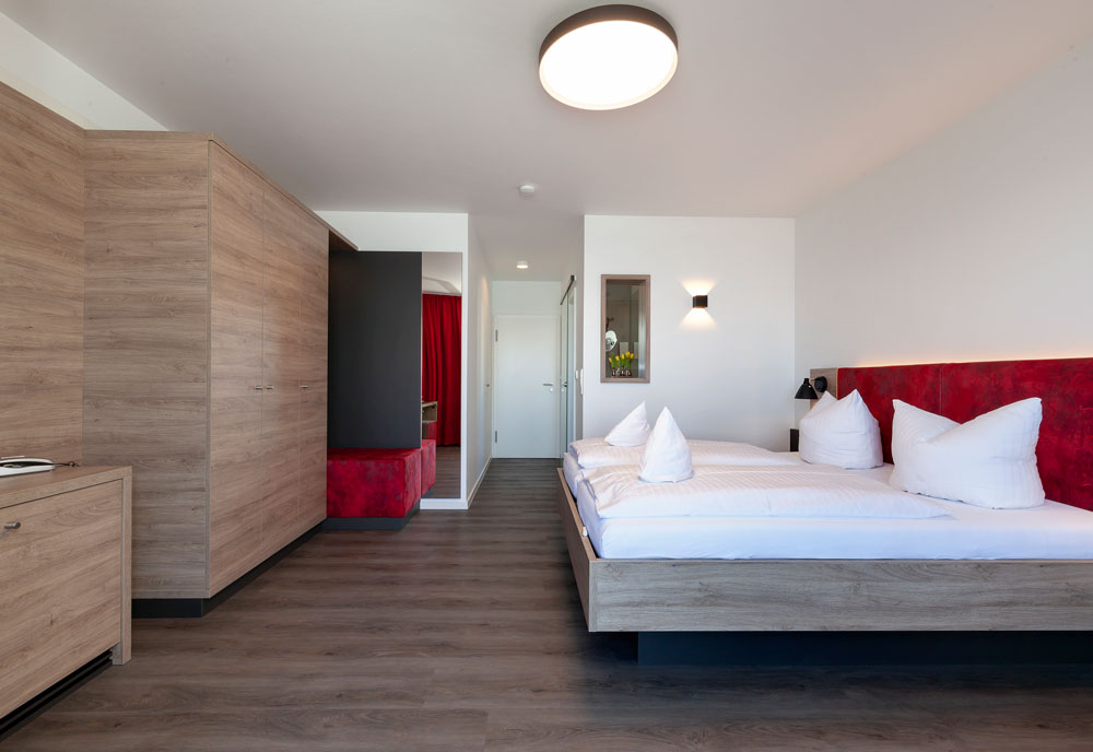Modernes Schlafzimmer mit Doppelbett, Holzfußboden und roten Akzenten