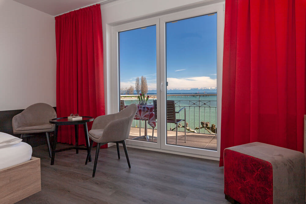 Schlafzimmer mit großem Fenster, Balkonzugang und roter Dekoration