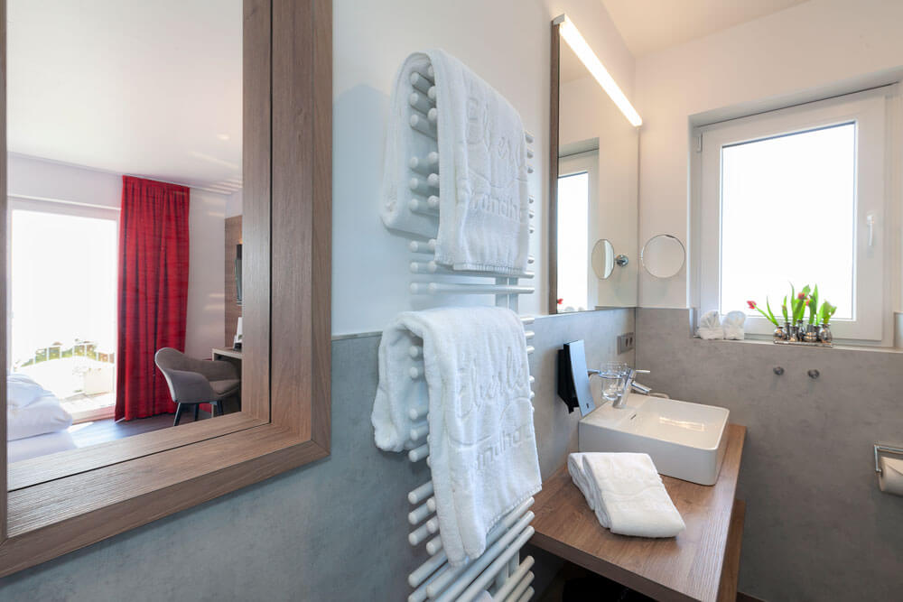 Elegantes Badezimmer mit Handtüchern, Spiegel und Glasdusche