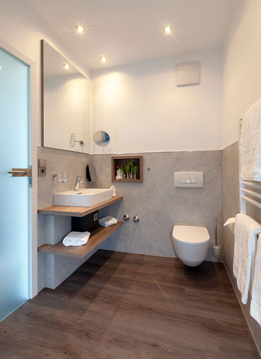 Modernes Badezimmer mit Waschbecken, WC und indirekter Beleuchtung
