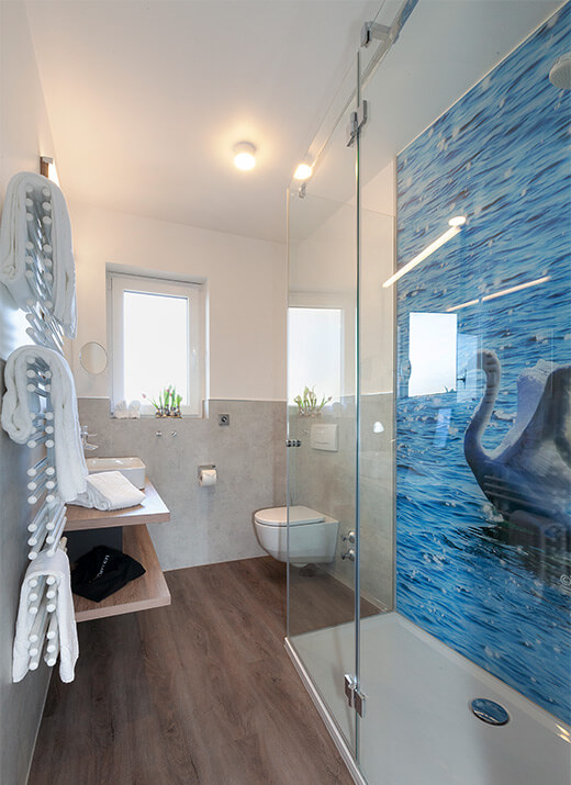 Helles Badezimmer mit Dusche, WC und blauer Fliesenwand