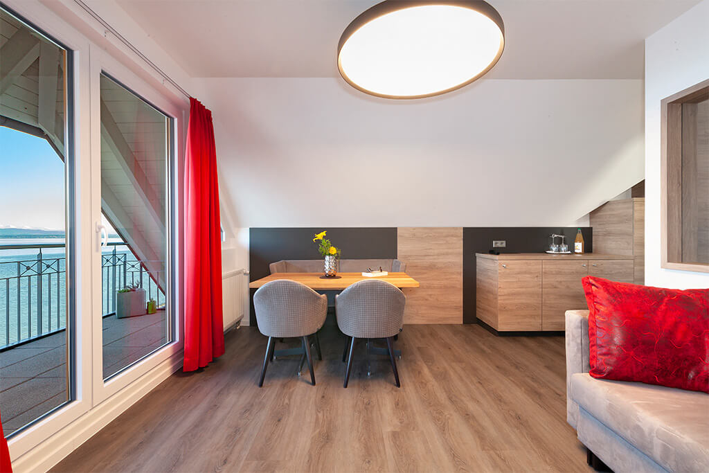Modernes Apartmentzimmer mit Essbereich, Küchenzeile und roten Vorhängen