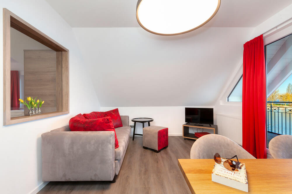 Gemütliches Apartmentzimmer mit Sofa, TV und kleinem Essbereich